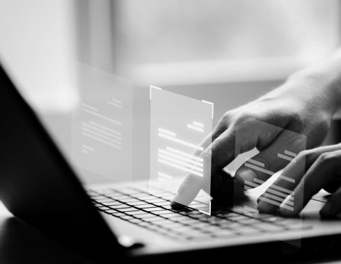 balck and white image of man typing on a laptop