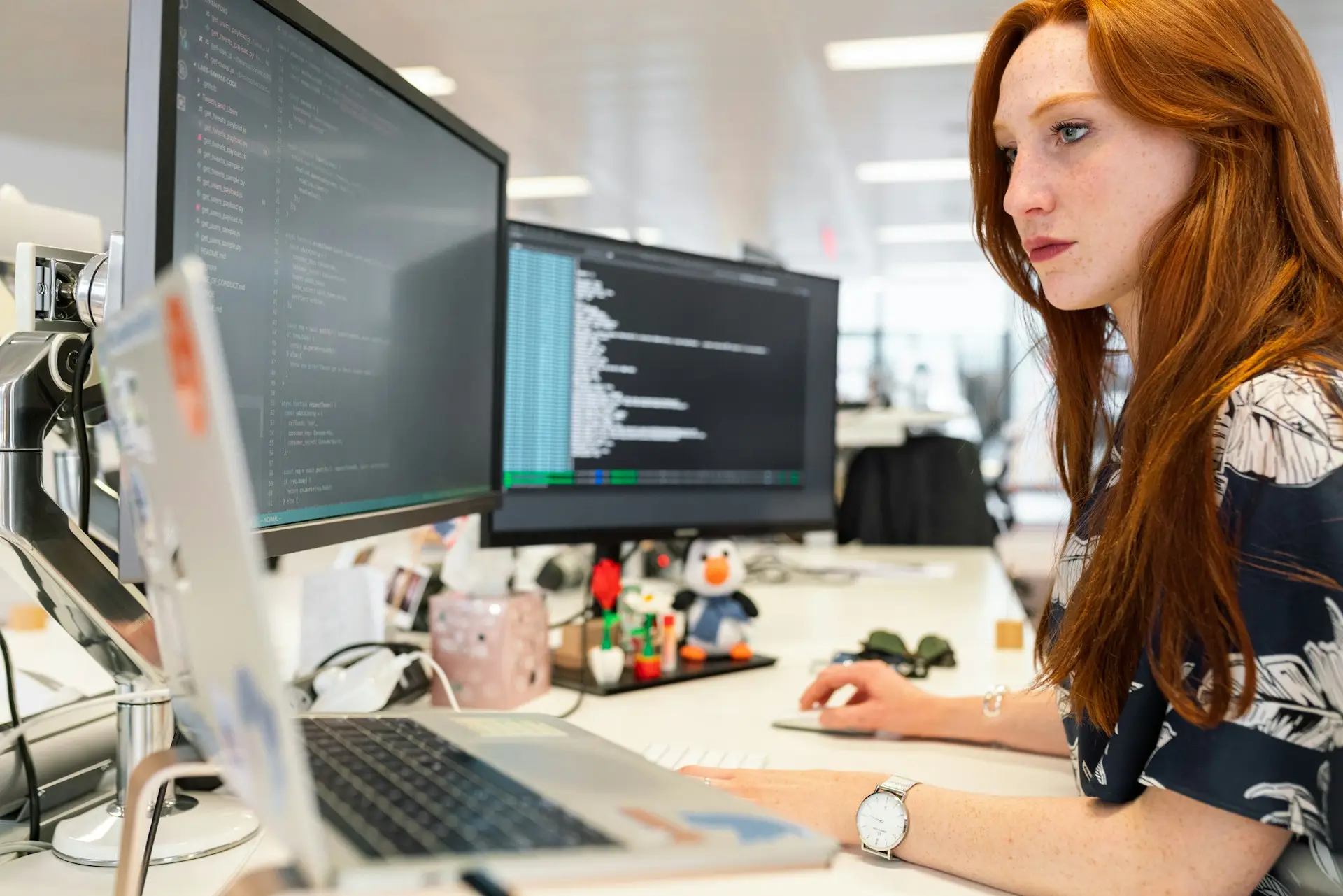 Girl sitting in front of two screens and coding